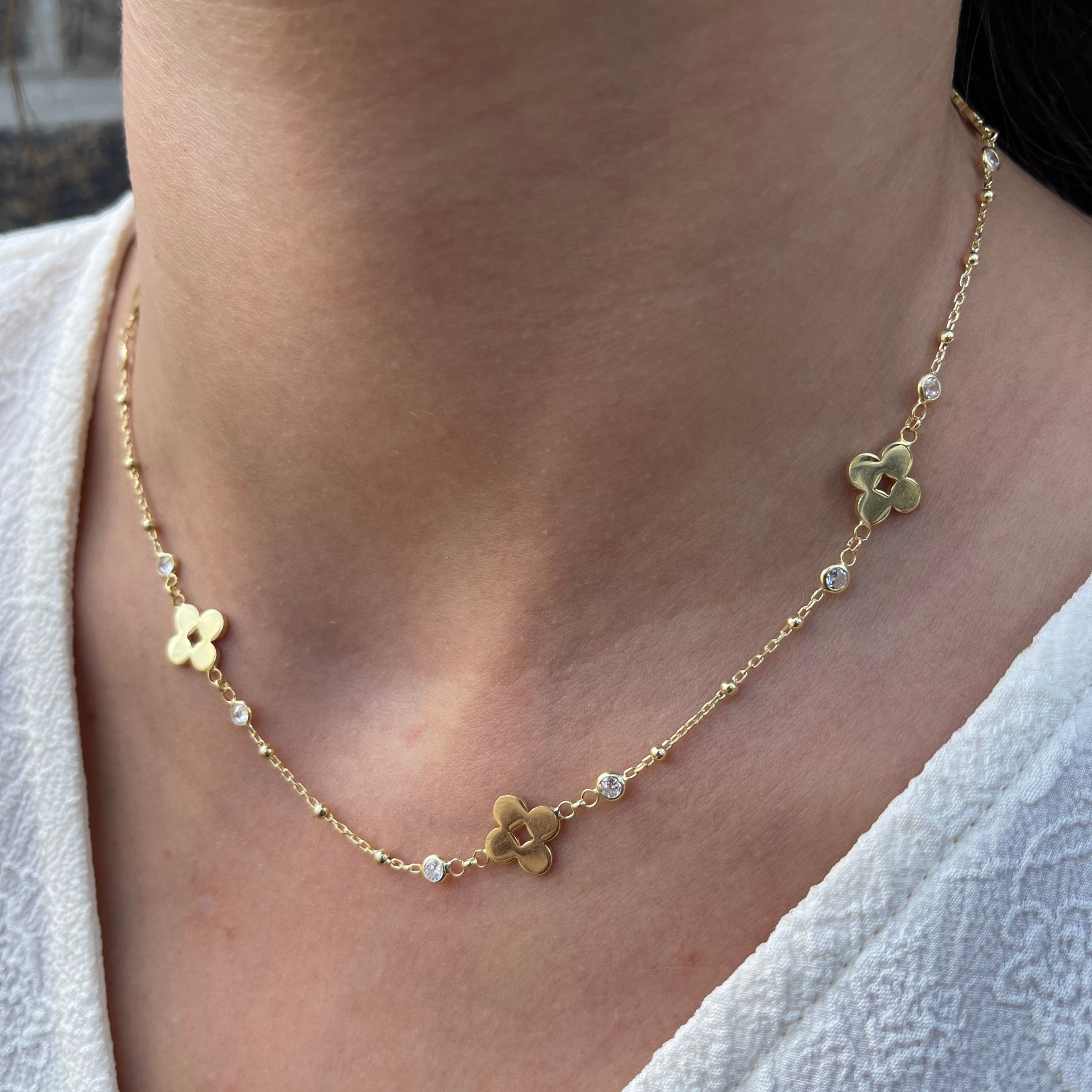 Ketting van 925 sterling zilver met klaverhangers en zirconia steentjes, gedragen rond de hals.