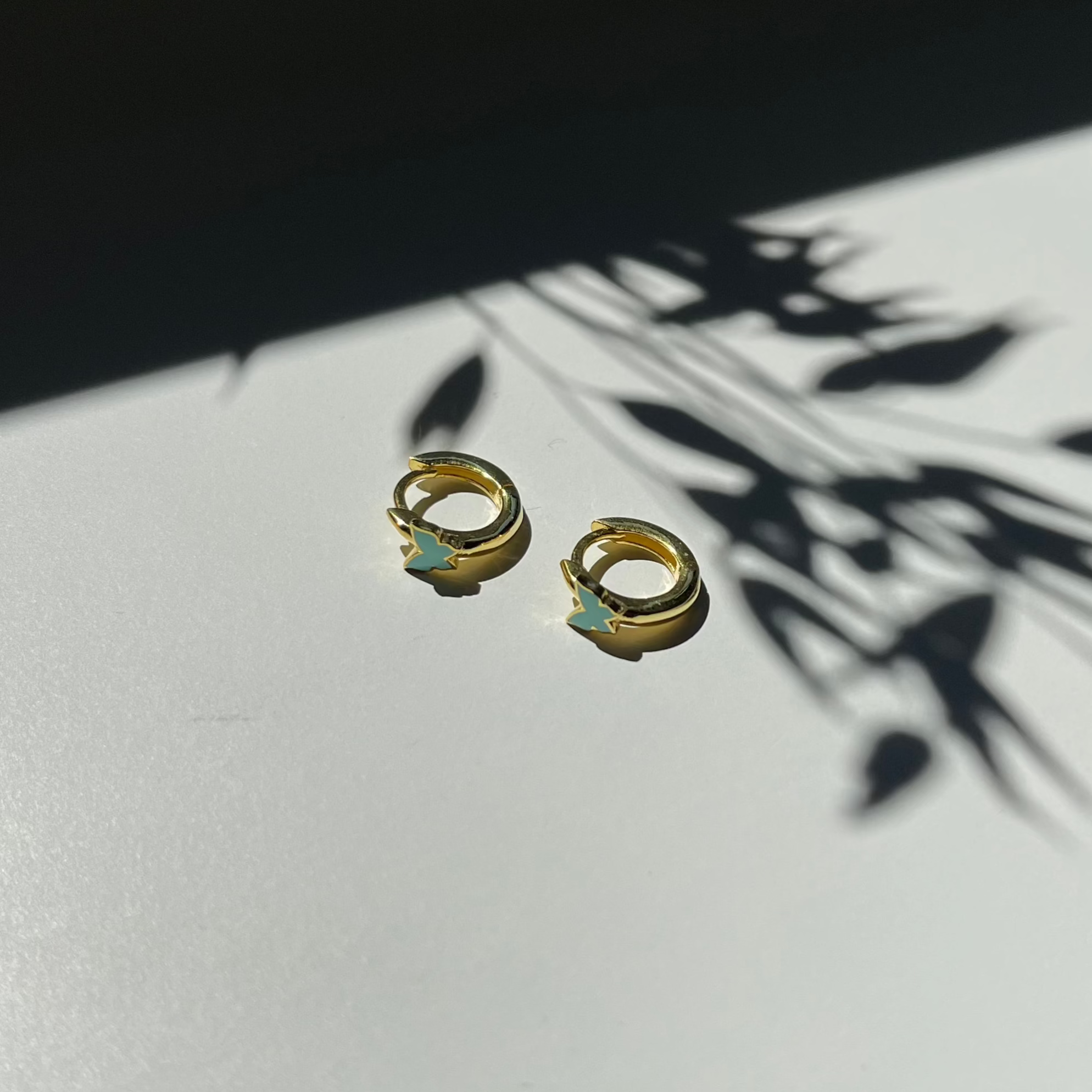 Kinderoorbellen met turquoise vlinderhanger aan een goudkleurige ring