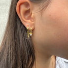 Close-up van gouden oorbel met hartje en dubbele ketting, gedragen in het oor