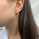 Gouden oorring met rechthoekige zirconia en dubbele ketting, gedragen aan het oor