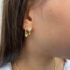 Close-up van gouden oorring met hartvormige zirconia steen