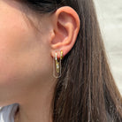 Gouden sparkle chain oorbel met subtiel kettinkje en fonkelende zirkonia, gedragen door een vrouw

