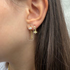 Close-up van gouden oorring met dubbele ketting en fonkelende zirconia